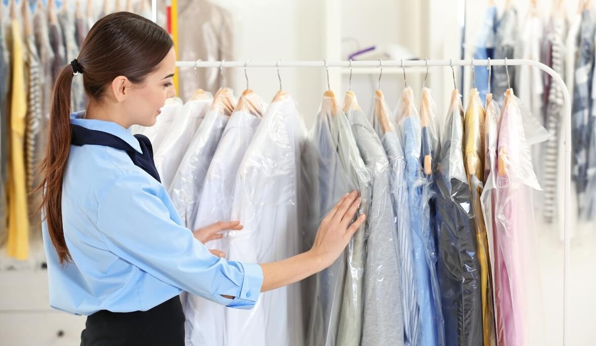 Dry cleaning staff inspecting neatly packed garments, showcasing clean clothes.